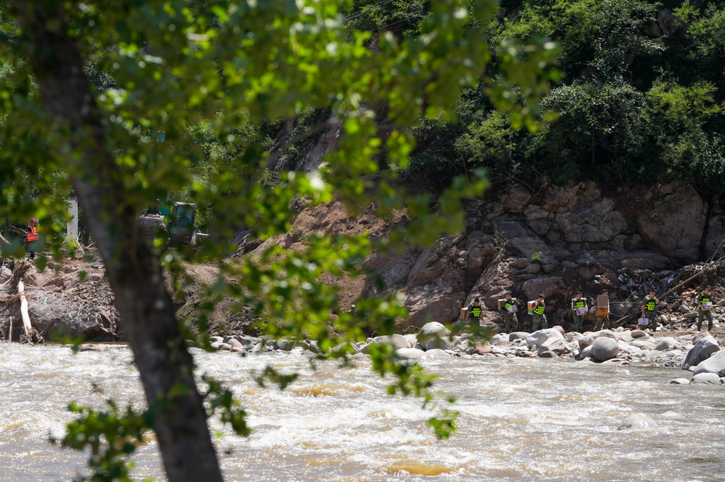 7月30日，在密云区冯家峪镇，救援人员为道路被阻断的村庄运送物资。