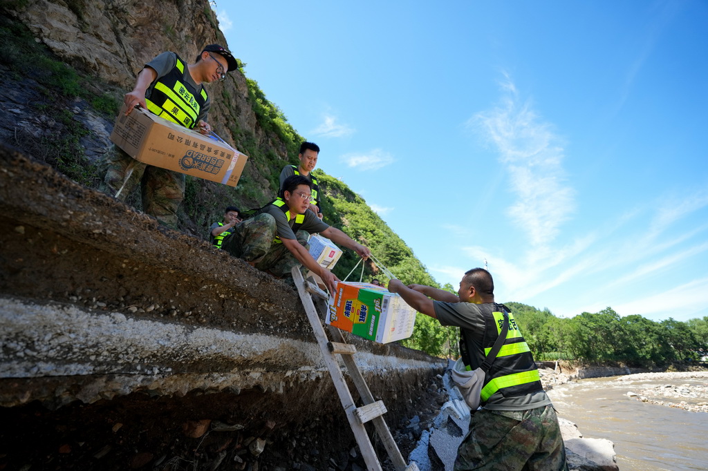 7月30日，在密云区冯家峪镇三岔口村，救援人员为村民运送物资。