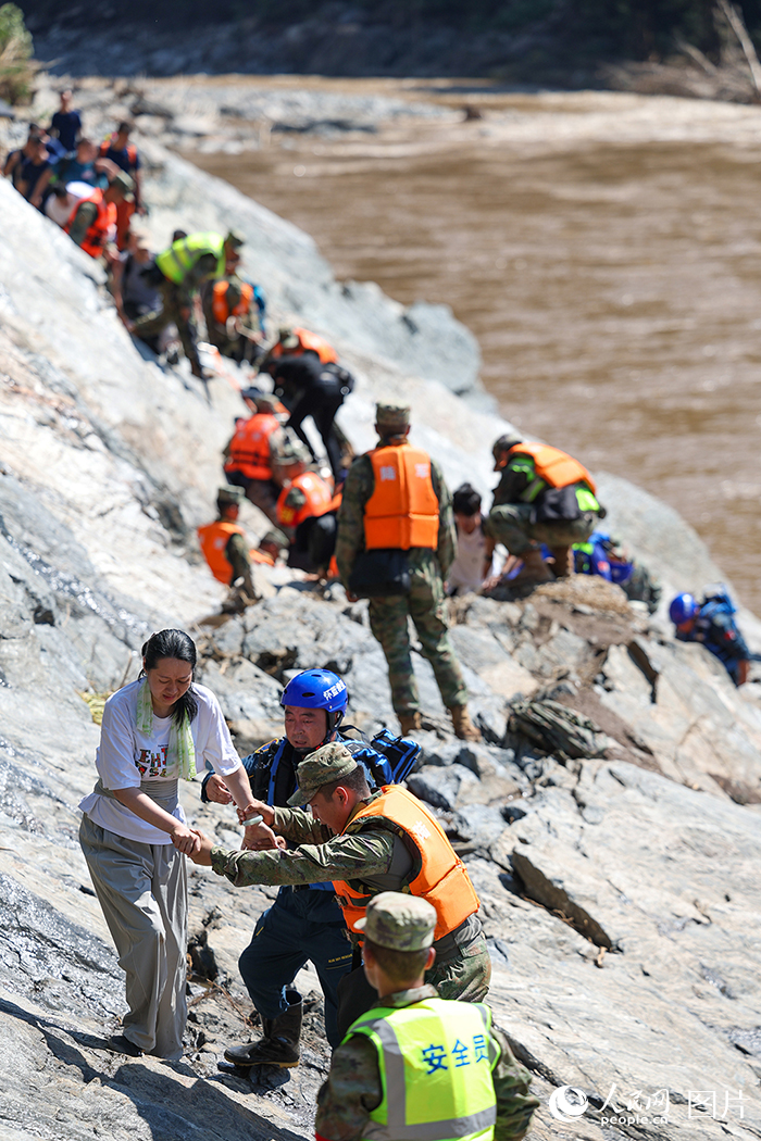 7月29日，北京市怀柔区琉璃庙镇双文铺村附近，解放军陆军某部官兵和蓝天救援队队员协助受困游客和村民们转移。