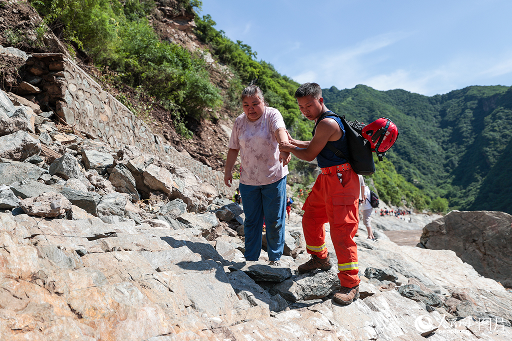 7月29日，北京市怀柔区琉璃庙镇双文铺村附近，救援人员协助受困游客和村民们转移。