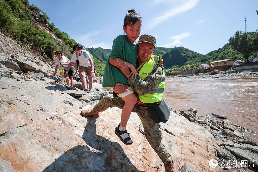 7月29日,北京市怀柔区琉璃庙镇双文铺村附近,解放军陆军某部官兵协助受困游客和村民们转移。