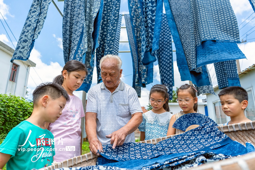 8月4日，国家级非遗南通蓝印花布印染技艺代表性传承人王振兴老人向小朋友介绍蓝印花布的制作技艺。