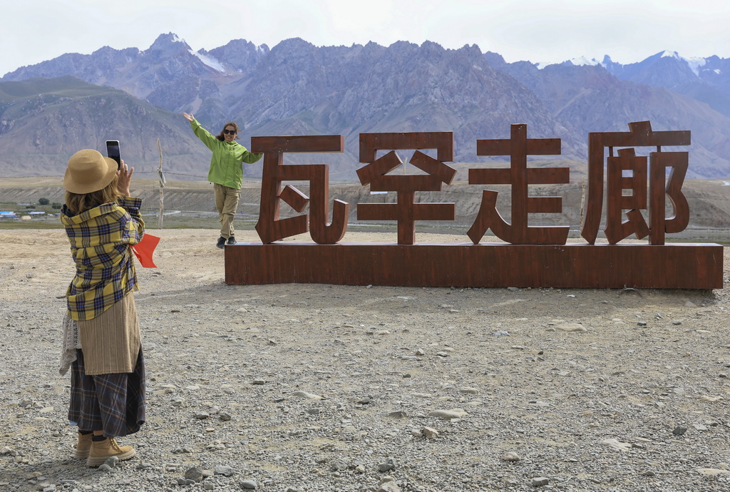 8月2日，游客在位于新疆塔什库尔干塔吉克自治县的瓦罕走廊入口处拍照留念。