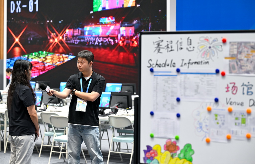 8月4日，媒体记者（右）在成都世运会主媒体中心媒体工作间采访。新华社记者 冯开华 摄