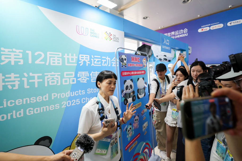 8月4日，工作人员（左一）在成都世运会主媒体中心为媒体记者介绍特许商品。新华社记者 王翔 摄