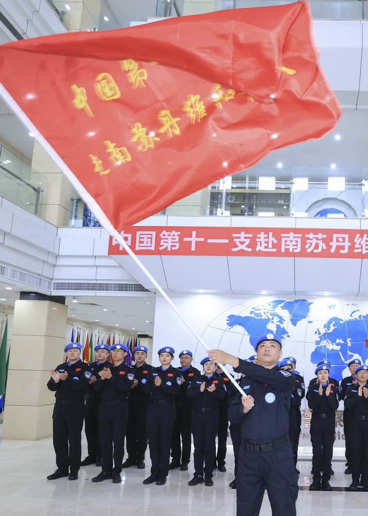 8月5日，中国第十一支赴联合国南苏丹任务区维和警队队长李冬（前）在出征仪式上展示队旗。