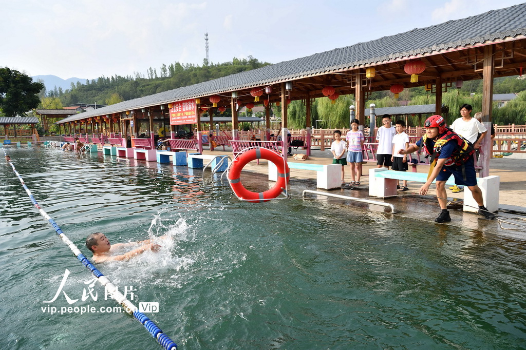 8月5日，消防员为学生们演示救生圈的使用方法。