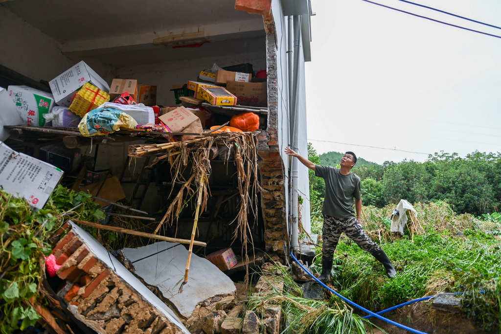 8月6日，广东清远佛冈县石角镇黄花村党委书记李庚原在一栋被冲毁的房屋旁了解房屋受损情况。