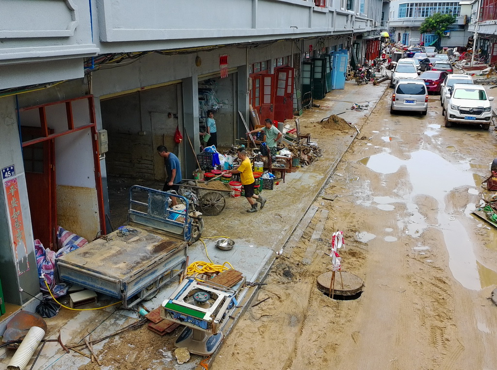 8月6日,村民在广东清远佛冈县石角镇黄花村清理屋内淤泥与杂物(无人机照片)。