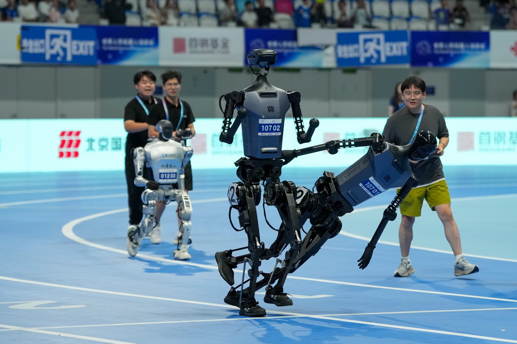 8月17日，在世界人形机器人运动会4x100米接力决赛中，来自天工队（前右）的人形机器人在交接棒时摔倒。