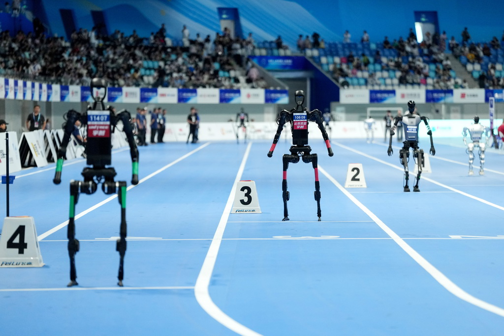 8月17日,在世界人形机器人运动会4x100米接力决赛中,来自行者泰山队(右一)、天工队(右二)、灵翌科技队(左二)和宇树科技队的人形机器人等待比赛开始。