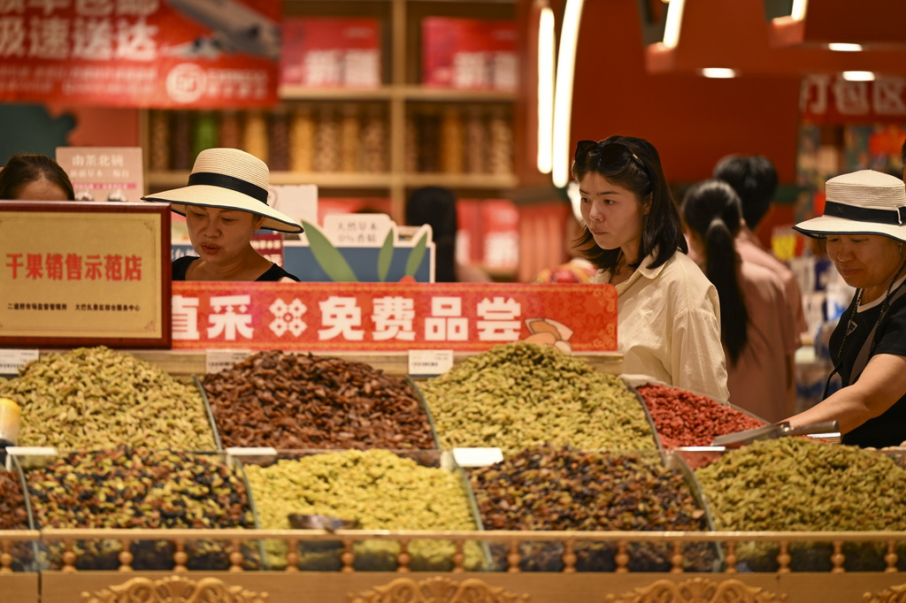 8月21日，游客在乌鲁木齐大巴扎步行街选购干果。
