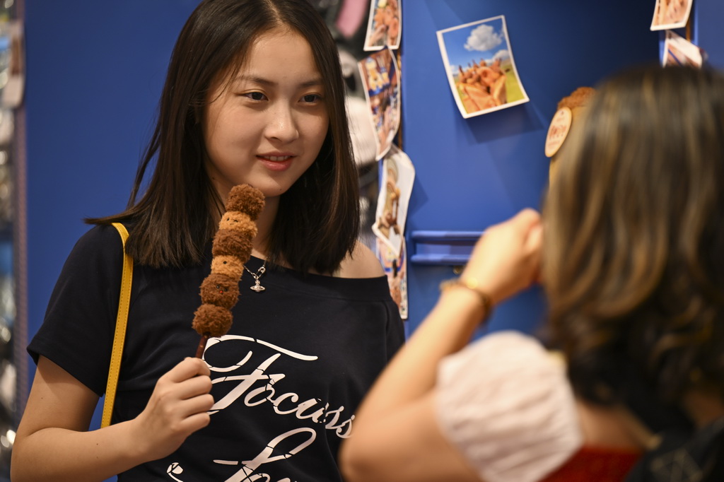 8月21日，在乌鲁木齐大巴扎步行街，游客手持文创产品拍照留影。