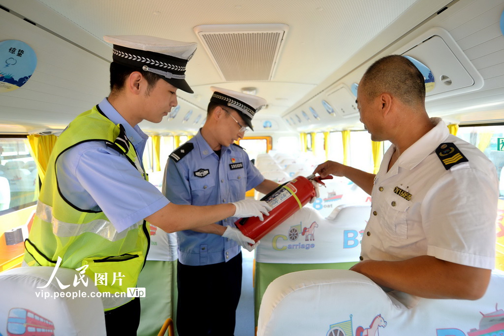 2025年8月22日，在山东省青岛市城阳区上马街道教育服务中心，交管中队民警在检查车内设置的灭火器。