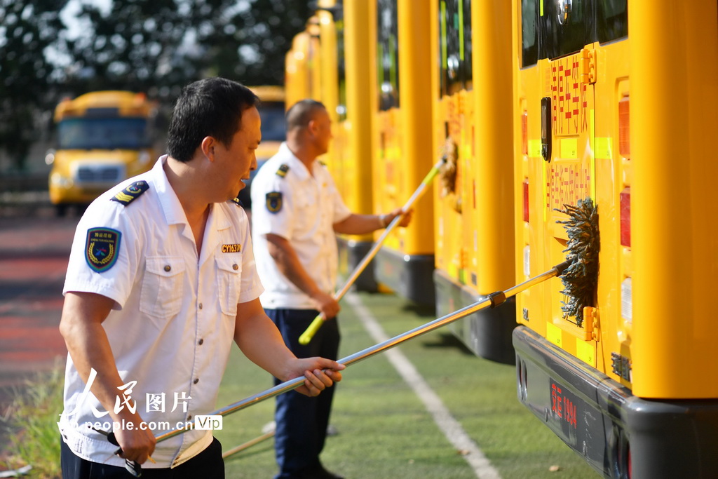 2025年8月22日，在山东省青岛市城阳区上马街道教育服务中心，技术人员和驾驶员在对校车进行维护。