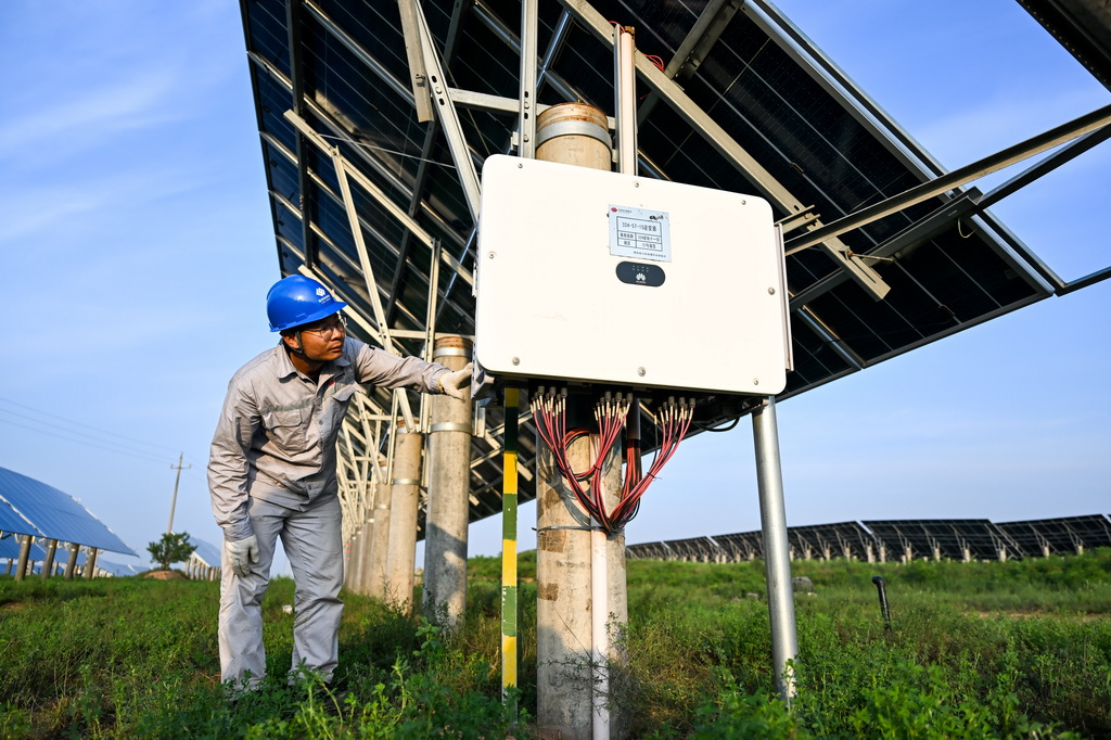 工人在天骄绿能50万千瓦采煤沉陷区生态治理光伏发电示范项目区巡查光伏发电设备（7月30日摄）。