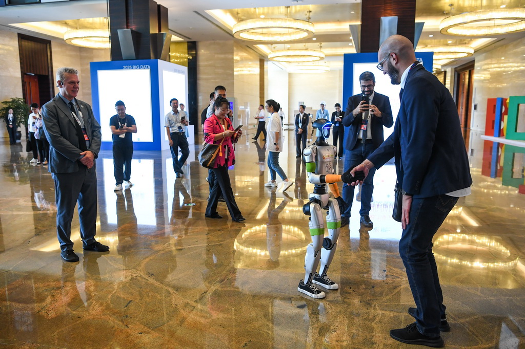 8月28日，参会人员在2025中国国际大数据产业博览会开幕式现场与一款机器人互动。