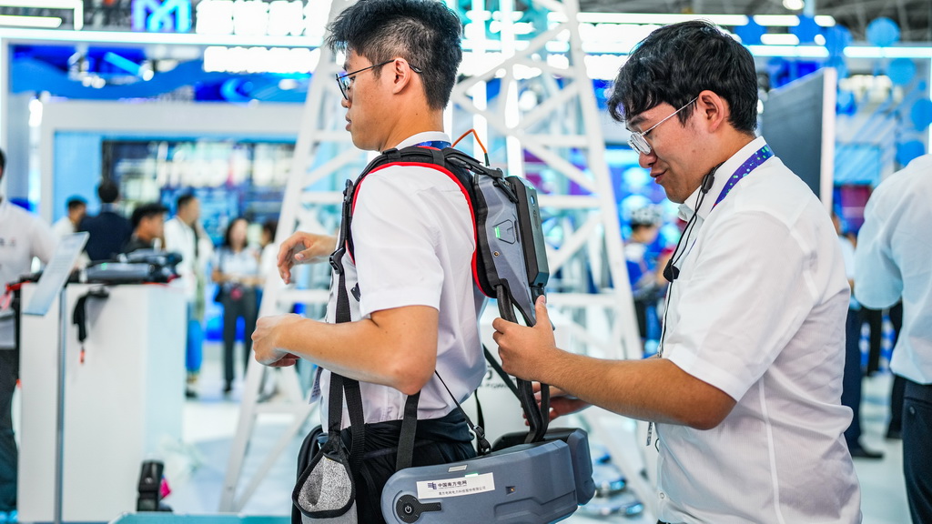 8月28日，南方电网工作人员在数博会上帮观展者佩戴攀登用外骨骼。新华社记者 陶亮 摄