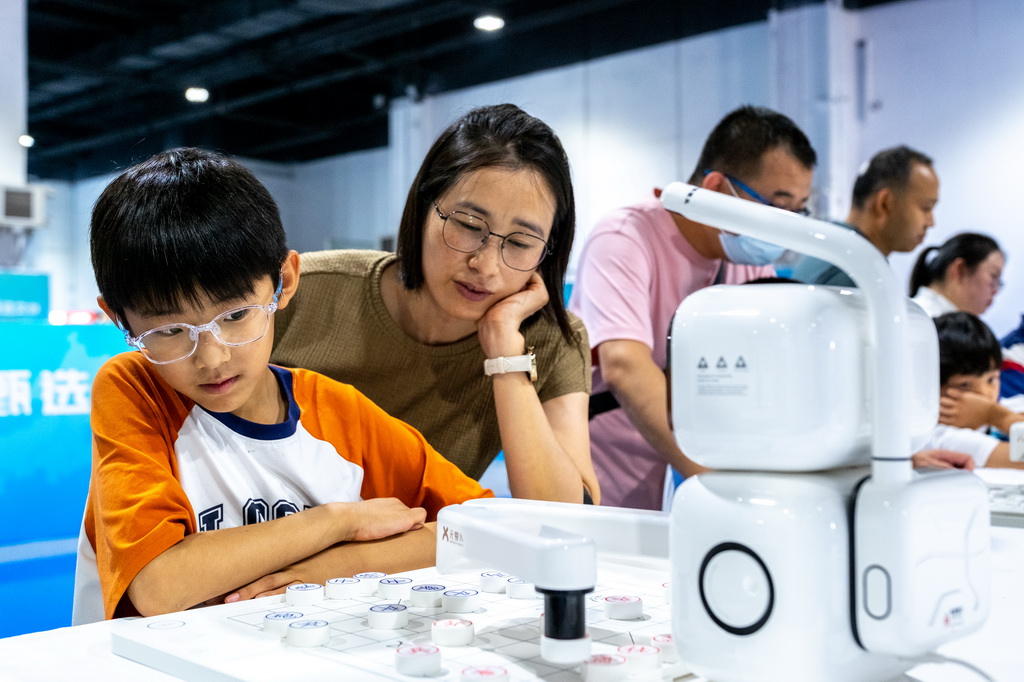 8月31日，在内蒙古呼和浩特市2025北疆书展，小朋友与AI下棋机器人对弈。
