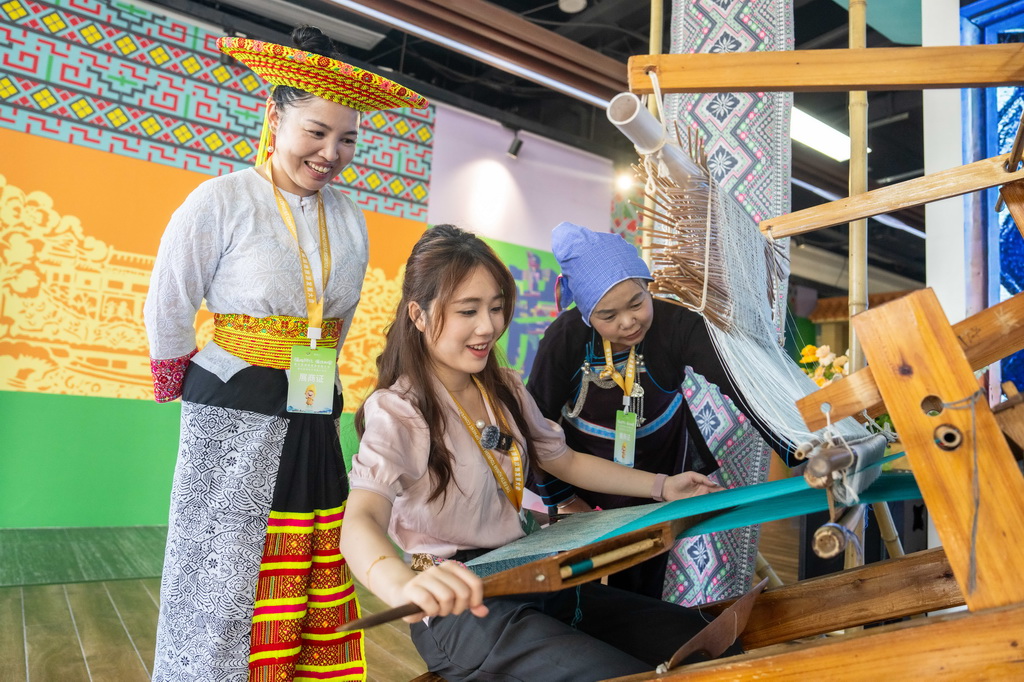 9月16日，在湖南省怀化市五溪非遗园，游客在体验侗族织锦技艺。