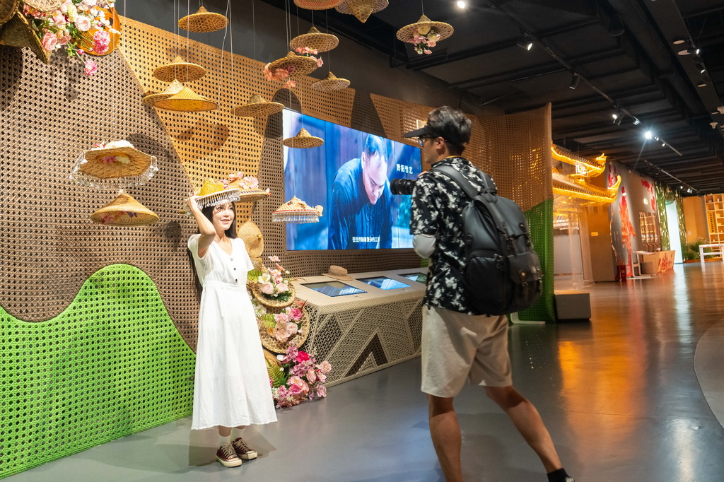 9月16日，在湖南省怀化市五溪非遗园，游客（左）在试戴黔阳竹艺编制的帽子。