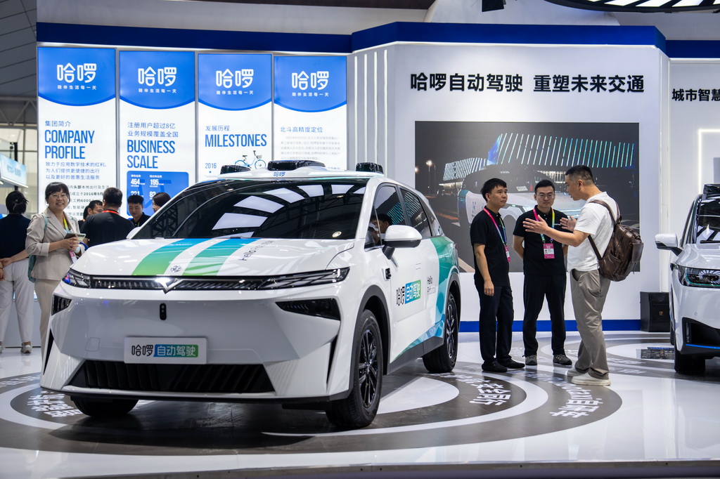 9月24日，在株洲国际会展中心，观众（右一）在了解一台配有北斗技术的自动驾驶汽车。