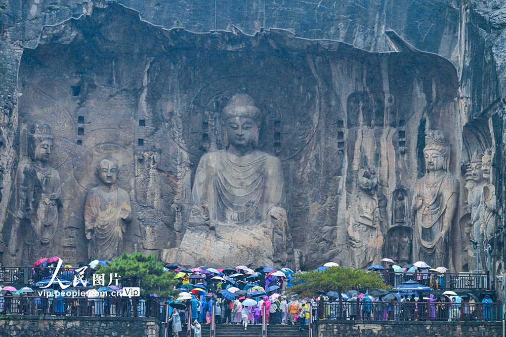 10月1日是国庆假期第一天，游客冒雨游览河南洛阳的龙门石窟。李卫超摄（人民图片网）