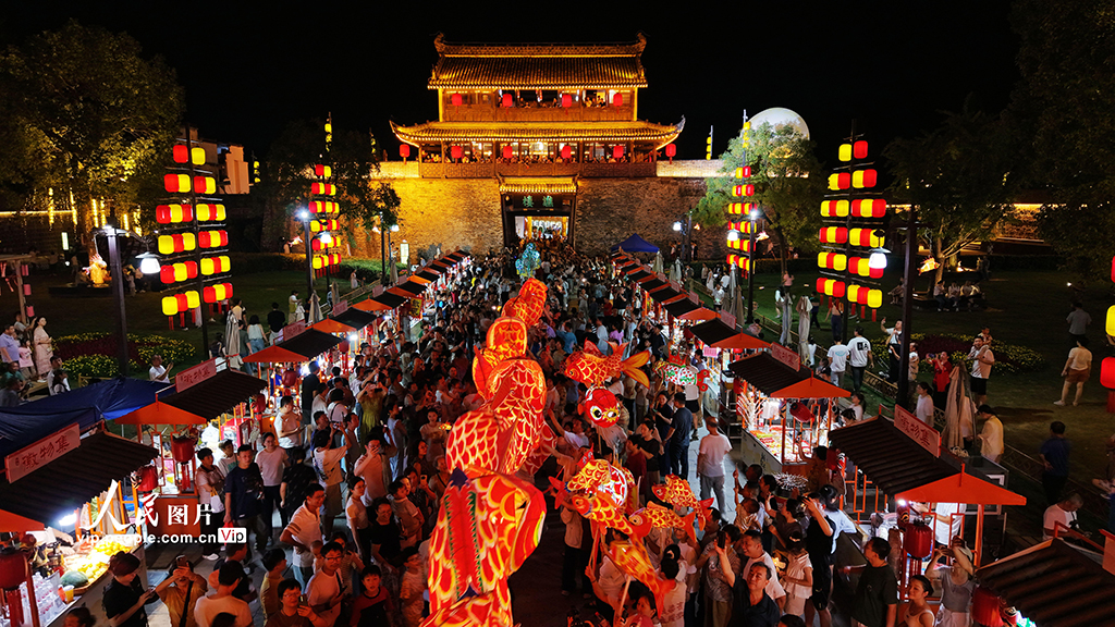 10月6日，游客在安徽歙县徽州古城观赏非遗鱼灯巡游表演，欢度中秋佳节。汪建林摄（人民图片网）