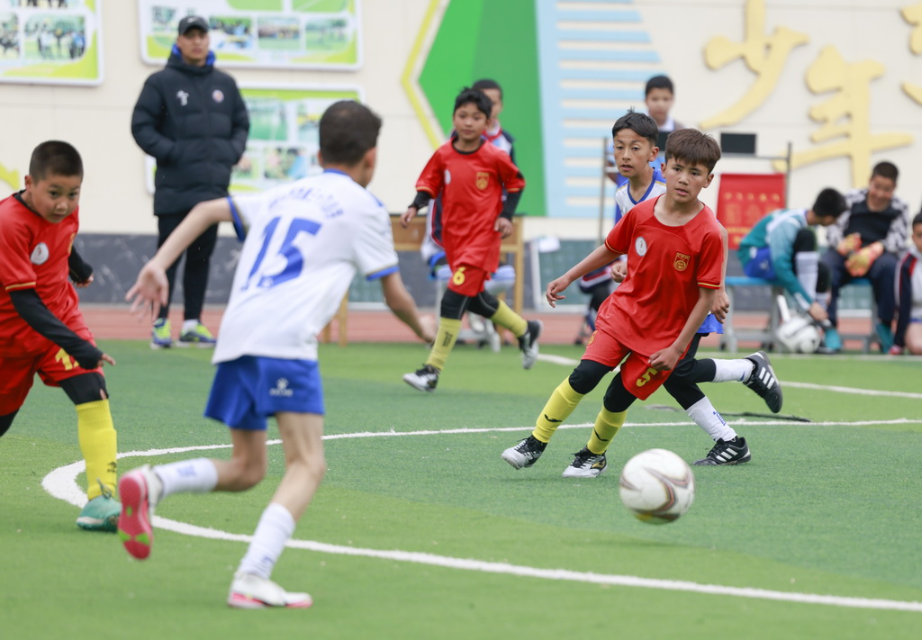 4月16日，在乌鲁木齐市水磨沟区第五届中小学足球联赛中，乌鲁木齐市第121小学足球队队员（红衣）在比赛中。新华社记者 王菲 摄