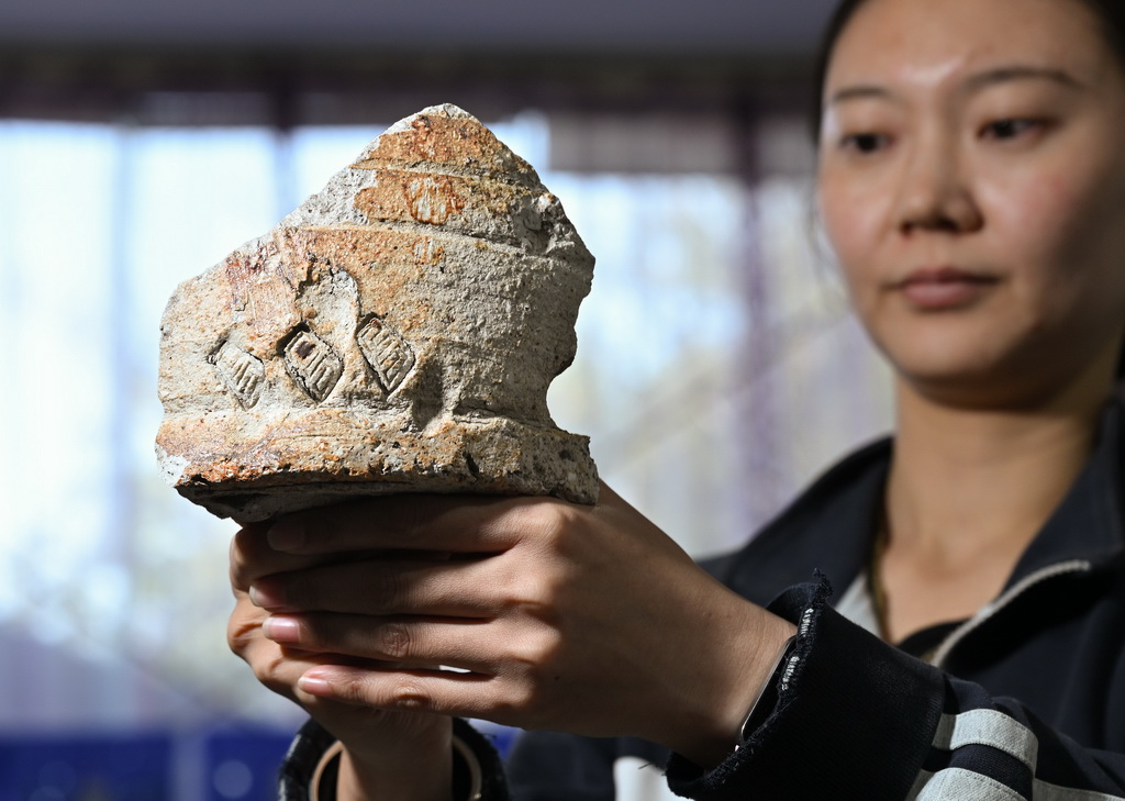一位工作人员在苏峪口瓷窑址考古队文物库房内展示遗址出土的带有“官”字款的匣钵残片（10月13日摄）。新华社记者 李贺 摄