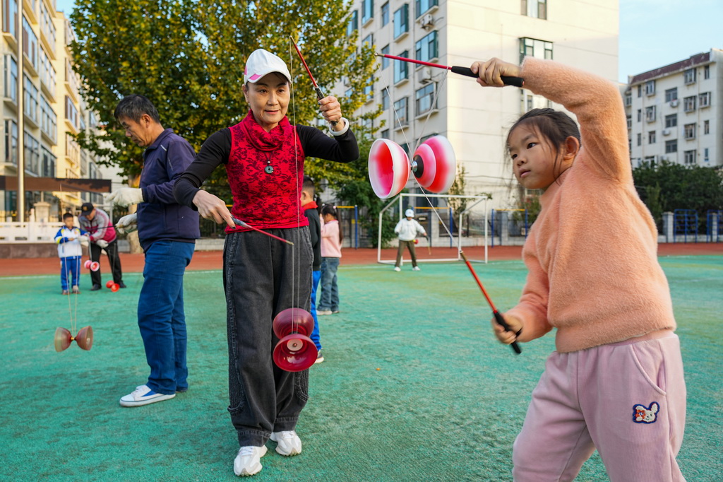 10月22日，志愿者在淄博市博山区中心路小学为学生们传授抖空竹。