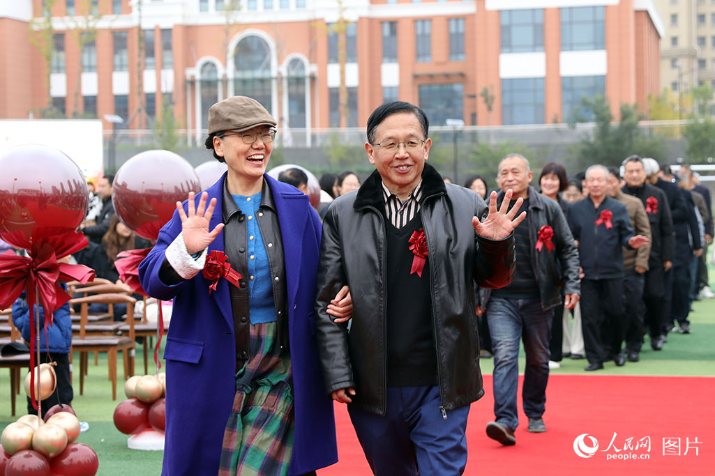 10月26日上午，山东省济南市高新区金谷小学操场，99对金婚老人在学生志愿者的引导与祝福下，携手踏上红毯，重现数十年前的美好瞬间。人民网记者 刘祺摄