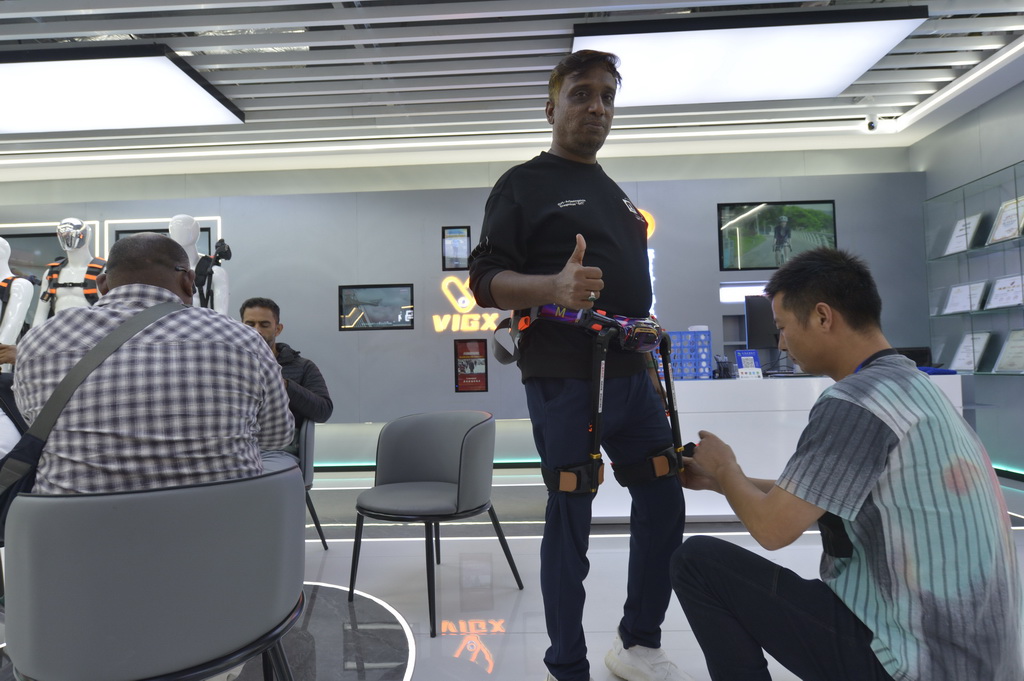 10月30日,在浙江省义乌市全球数贸中心的一家商店内,一名外籍商人试穿机械外骨骼。