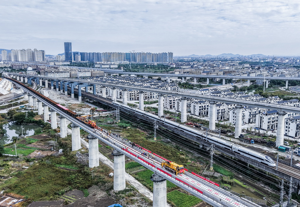 11月5日,在浙江省台州市杭台高铁温岭至玉环段施工作业现场,中铁十四局工作人员操作长轨牵引车进行铺轨作业(无人机照片)。