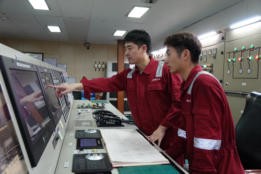 北京时间11月8日，大管轮董恒（左）在集控室内为机工田健伟讲解主要设备报警信息。新华社记者 顾天成 摄