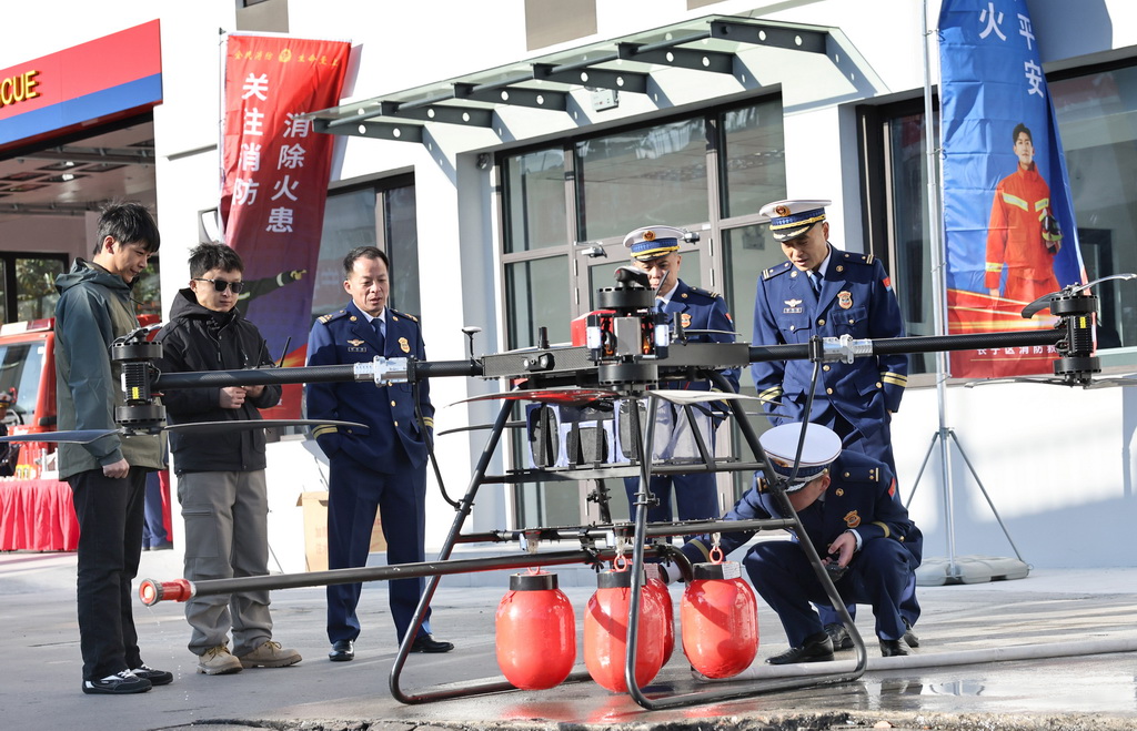 11月18日,消防员在活动现场查看消防无人机下方挂载的红色灭火弹。