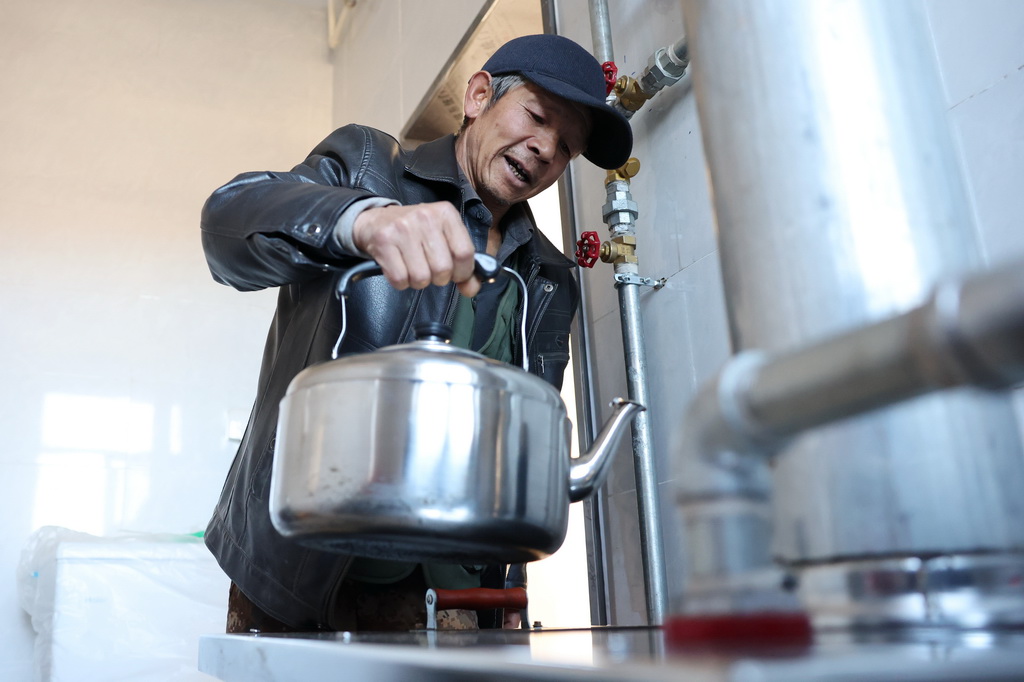 12月1日,在榆中县马坡乡旧庄沟村安置点,村民王建武在新家烧水。