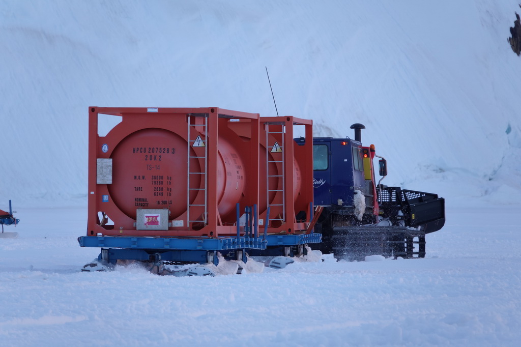 北京时间12月3日凌晨,雪地车拉着加满燃油的油罐离开“雪龙2”号,驶向中山站。