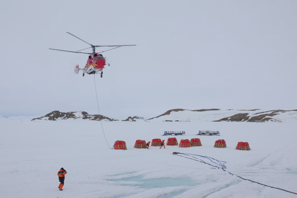 北京时间12月2日傍晚，“雪鹰102”直升机从“雪龙”号甲板飞至“雪龙2”号船侧冰面作业点，开启油囊吊挂作业。