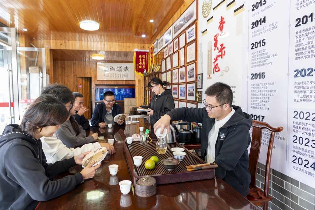 12月2日，返乡创业大学生杜赢（右一）向村民介绍白茶的加工制作工艺。