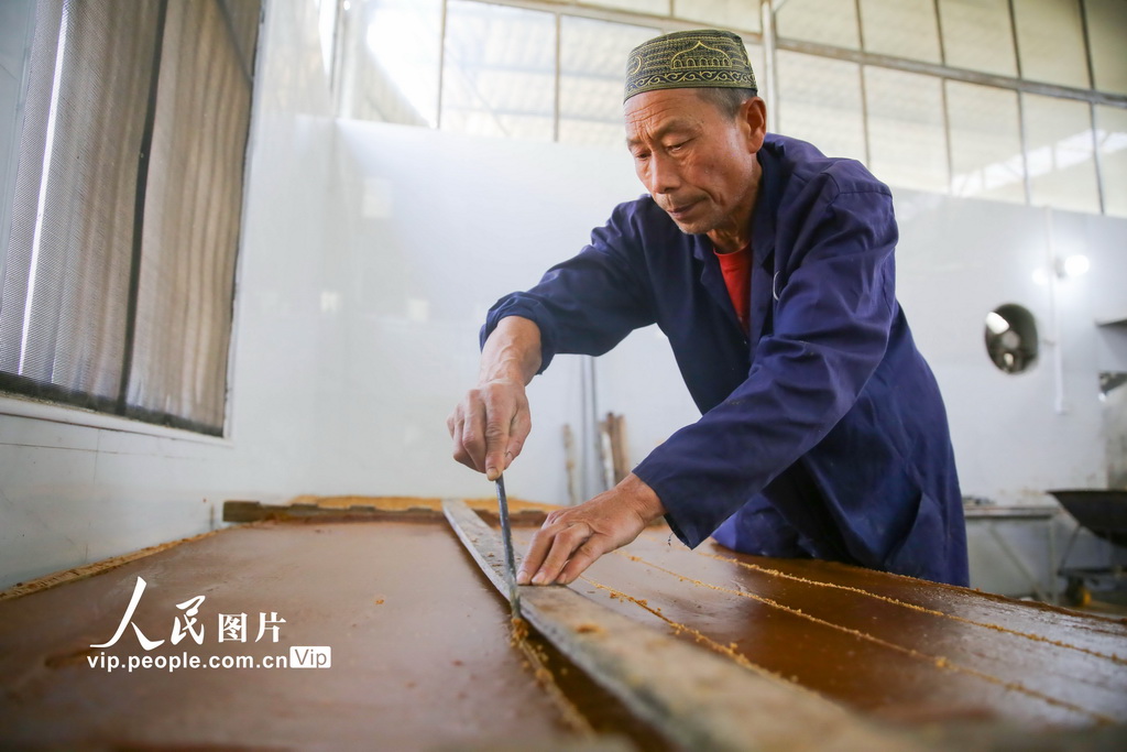 2025年12月6日,湖南省邵阳市隆回县山界回族乡老屋村,工人将冷却的红糖划块。
