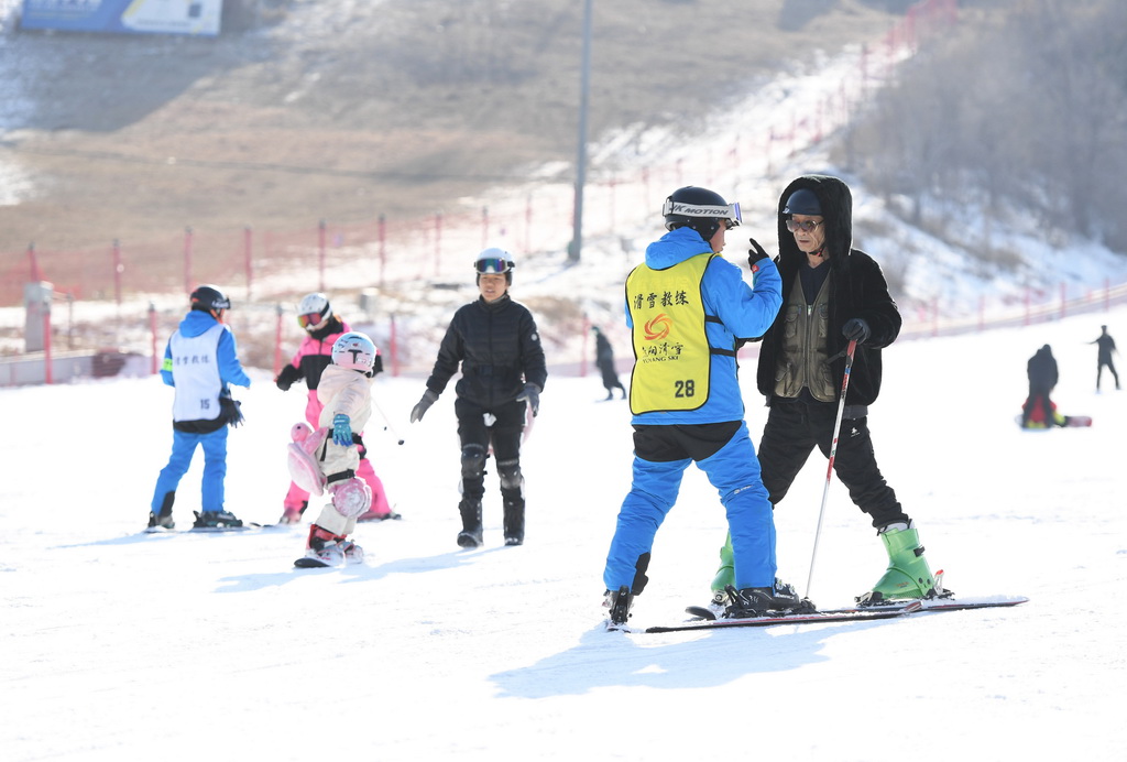 12月9日，市民（前右一）在北京渔阳国际滑雪场学习滑雪。