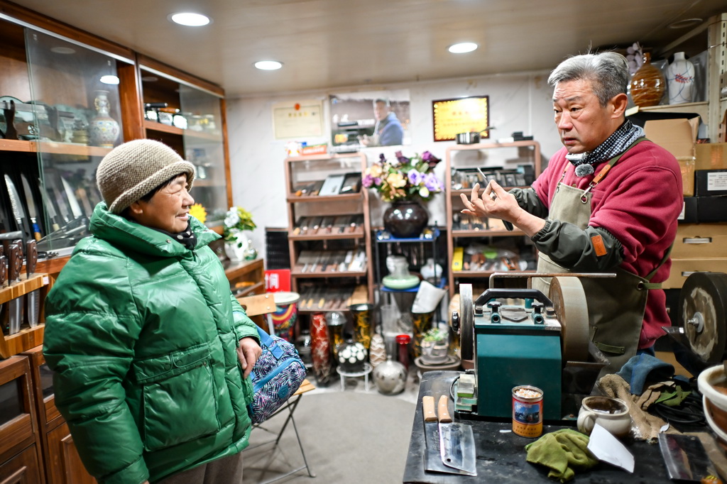 12月9日,商户(右)在为顾客介绍刀具。新华社记者 张铖 摄