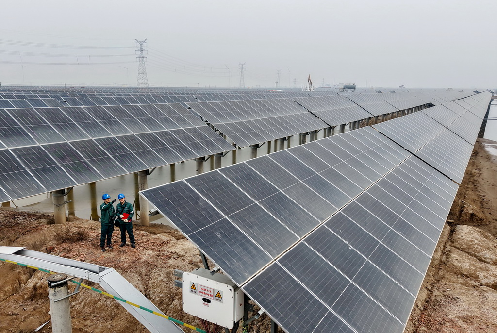 12月10日，国网沧州供电公司的工人在辖区渤海新区黄骅市一处“渔光互补”光伏发电场巡检（无人机照片）。