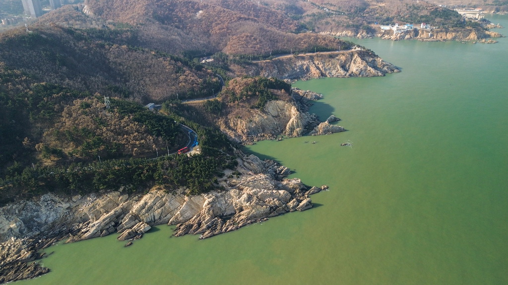 12月9日，车辆在威海市沿海岸线的自驾旅游公路上行驶（无人机照片）。