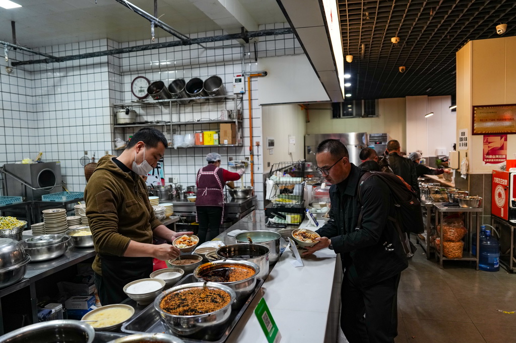 12月12日，在四川省广元市一家凉面馆，工作人员（左）在调配凉面调料。新华社记者 黄伟 摄