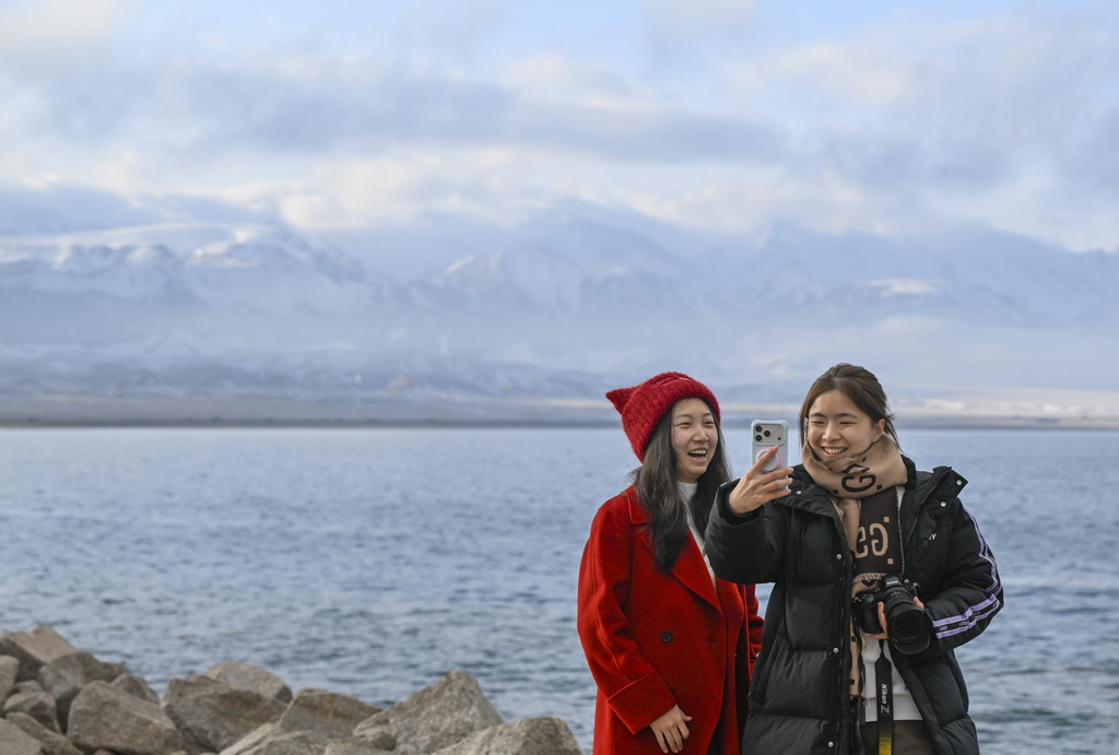 游客在赛里木湖边游玩留影（12月16日摄）。