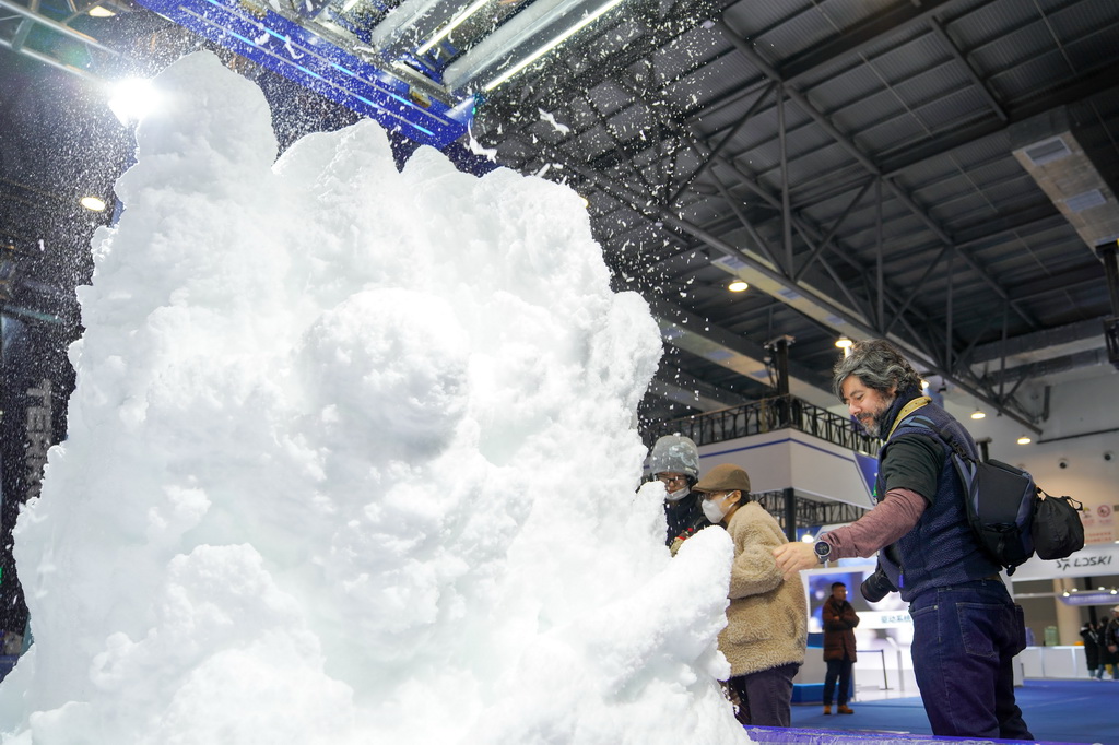 12月18日，外国媒体记者在第九届吉林冰雪产业国际博览会现场参观中国制造的造雪机。