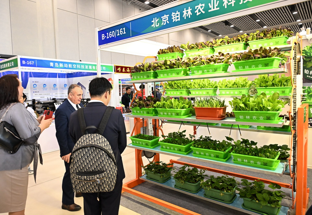 12月19日，客商在博览会上观看旋转种植设备演示。