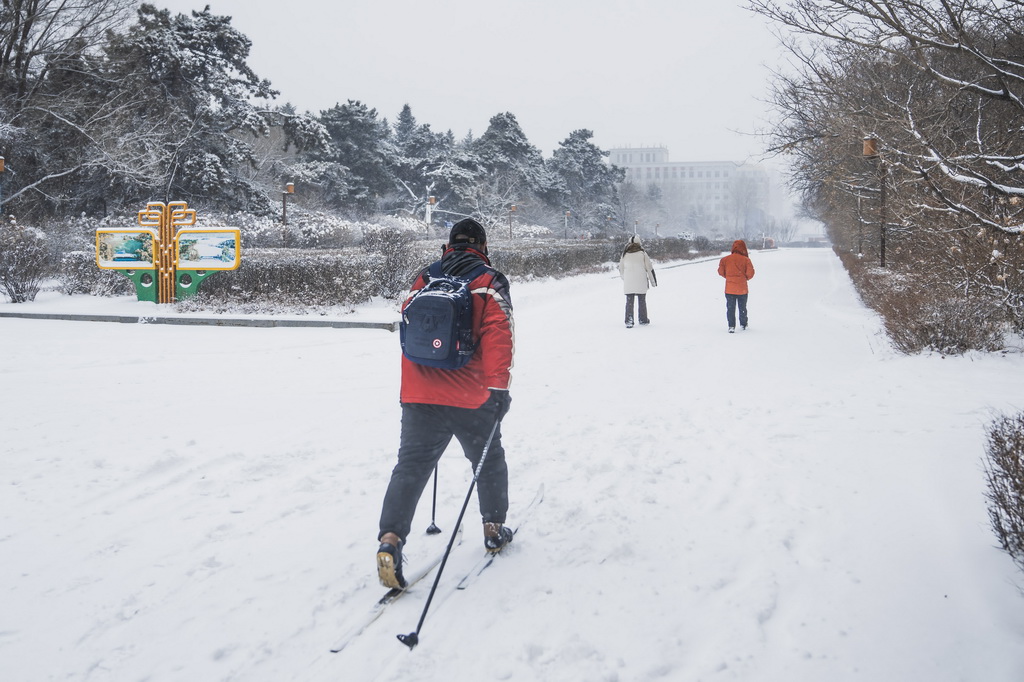 12月23日，一名长春市民踩着滑雪板冒雪出行。